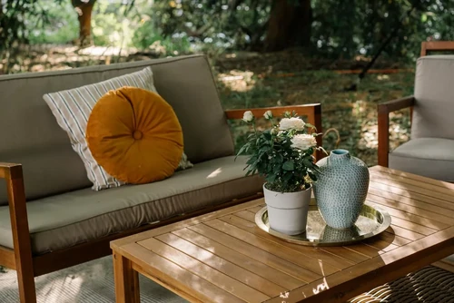Patio furniture in Pearl, MS, including a couch with green cushions and a wooden table with decorative plants.