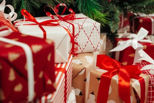 Close-up of wrapped holiday gifts with red ribbons and patterned paper.