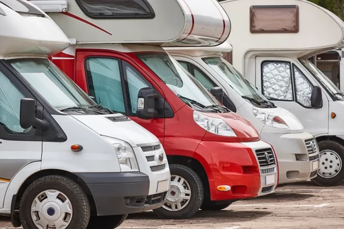 Row of RVs parked side by side in outdoor lot.