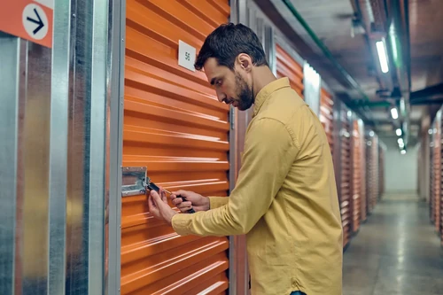 Man locking a storage unit with a padlock.